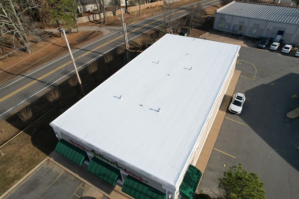 An aerial view of a large building with a white roof.