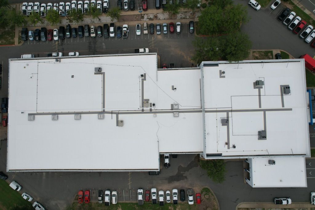An aerial view of a large building with a white roof.