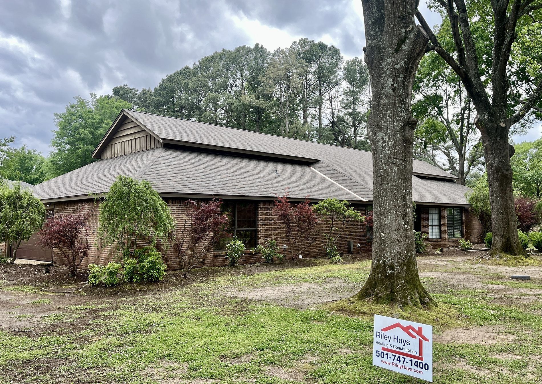 A house with a new roof and a sign in front of it.
